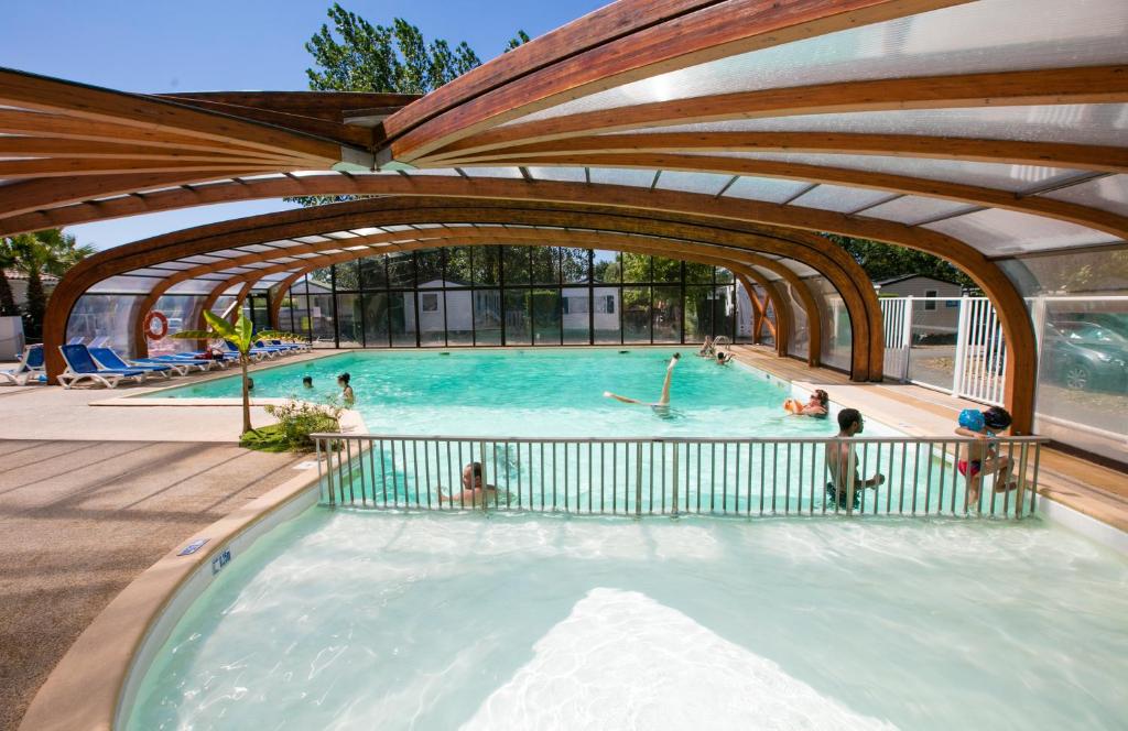 a swimming pool with people in the water at Domaine de La Marina in Messanges