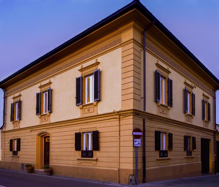 un grand bâtiment jaune avec des fenêtres à volets noirs dans l'établissement Villa Antiche Mura, à Empoli