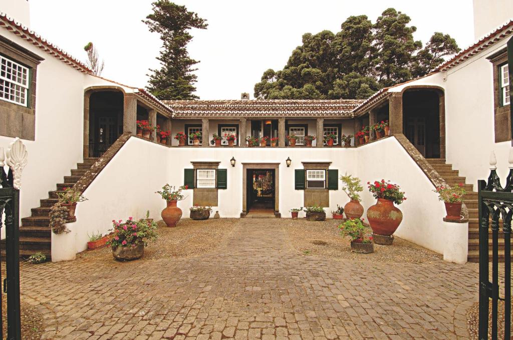 ein großes weißes Gebäude mit Treppen und Topfpflanzen in der Unterkunft Casa das Calhetas - Turismo de Habitação in Calhetas