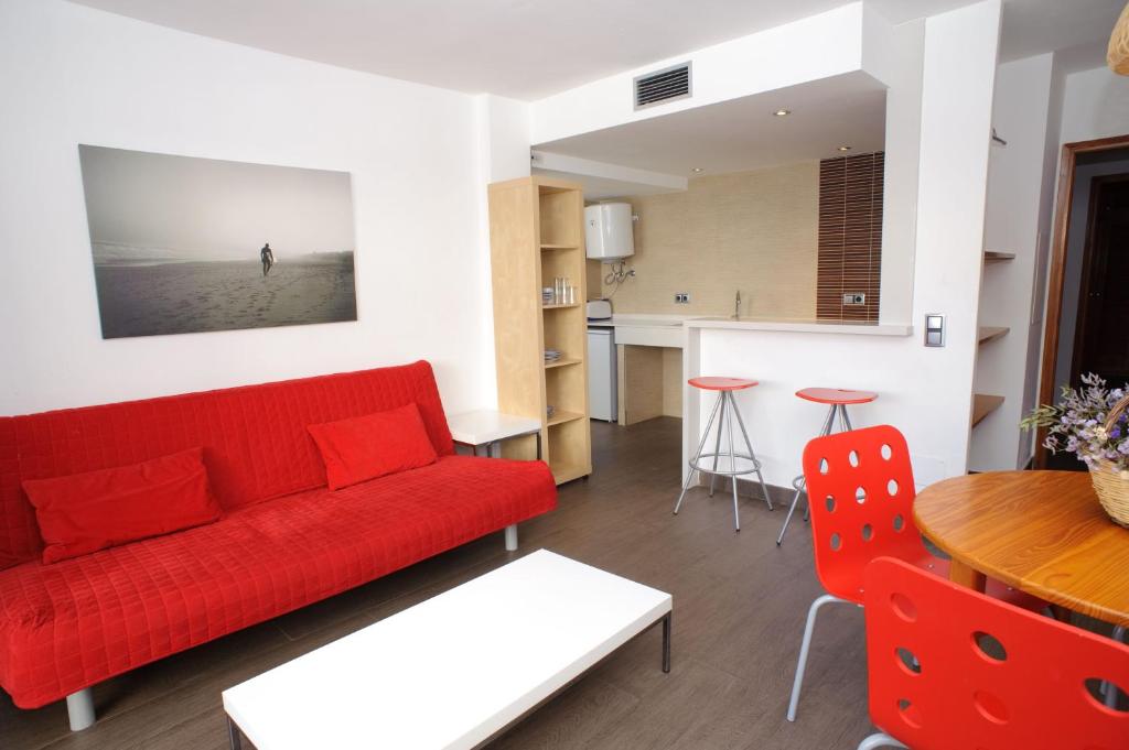 a living room with a red couch and a table at Apartamentos San Francisco in San Antonio