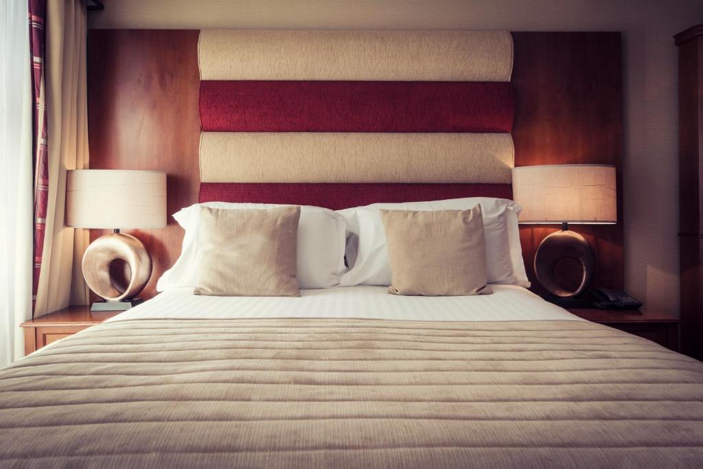 a bedroom with a large bed with two lamps at Carlton George Hotel in Glasgow