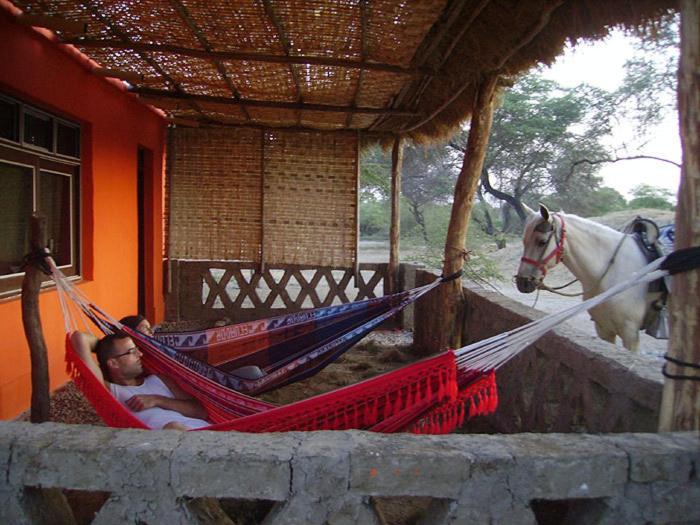 a man laying in hammocks with a horse in a house at Rancho Santana Horseback Riding in Pacora