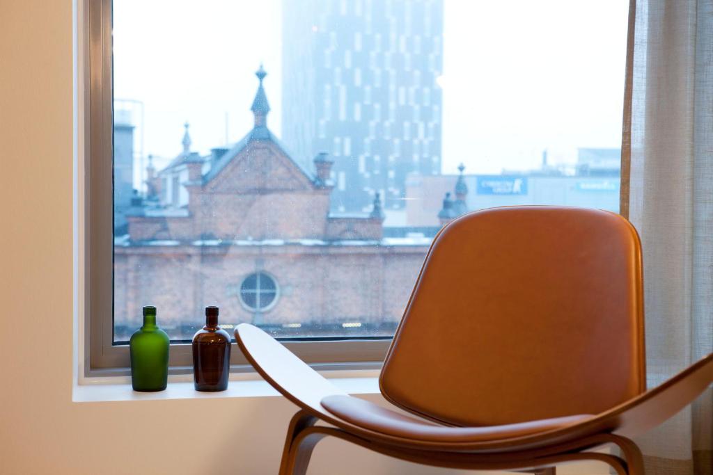 una sedia seduta davanti a una finestra con due bottiglie di Luminary 21 a Tampere