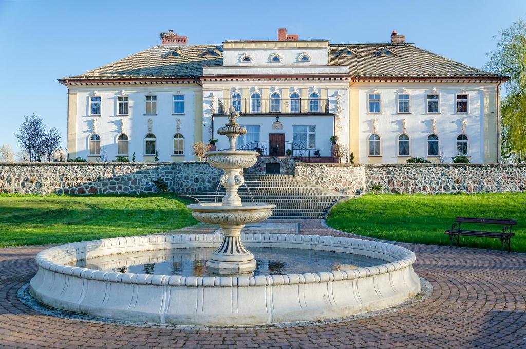 a fountain in front of a large house at Pałac pod Bocianim Gniazdem in Runowo