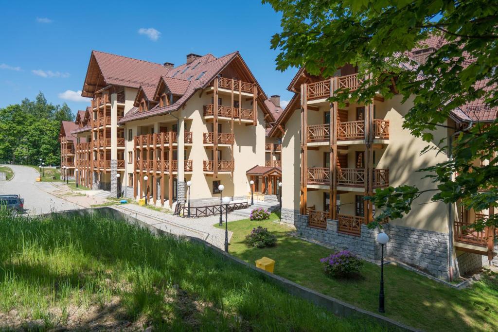 duży budynek z drewnianymi balkonami przy ulicy w obiekcie RentPlanet - Apartamenty Szrenica w Szklarskiej Porębie