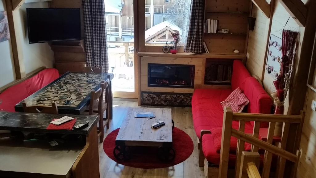 ヴァールにあるchalet des rennesのリビングルーム(赤いソファ、暖炉付)