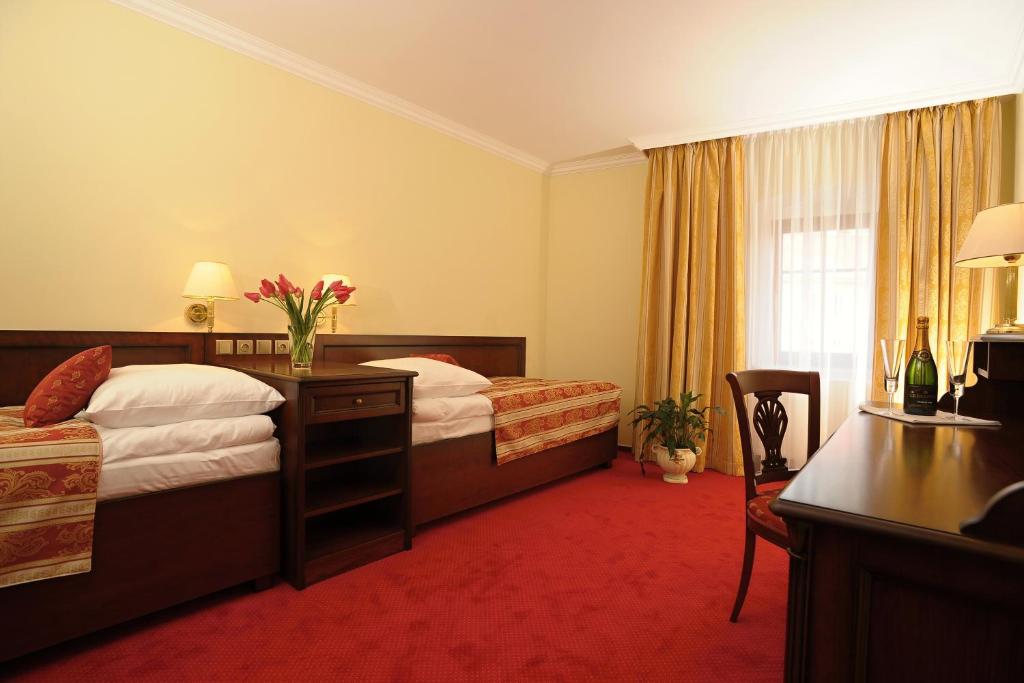 a hotel room with two beds and a desk at Hotel U Krále in Jičín