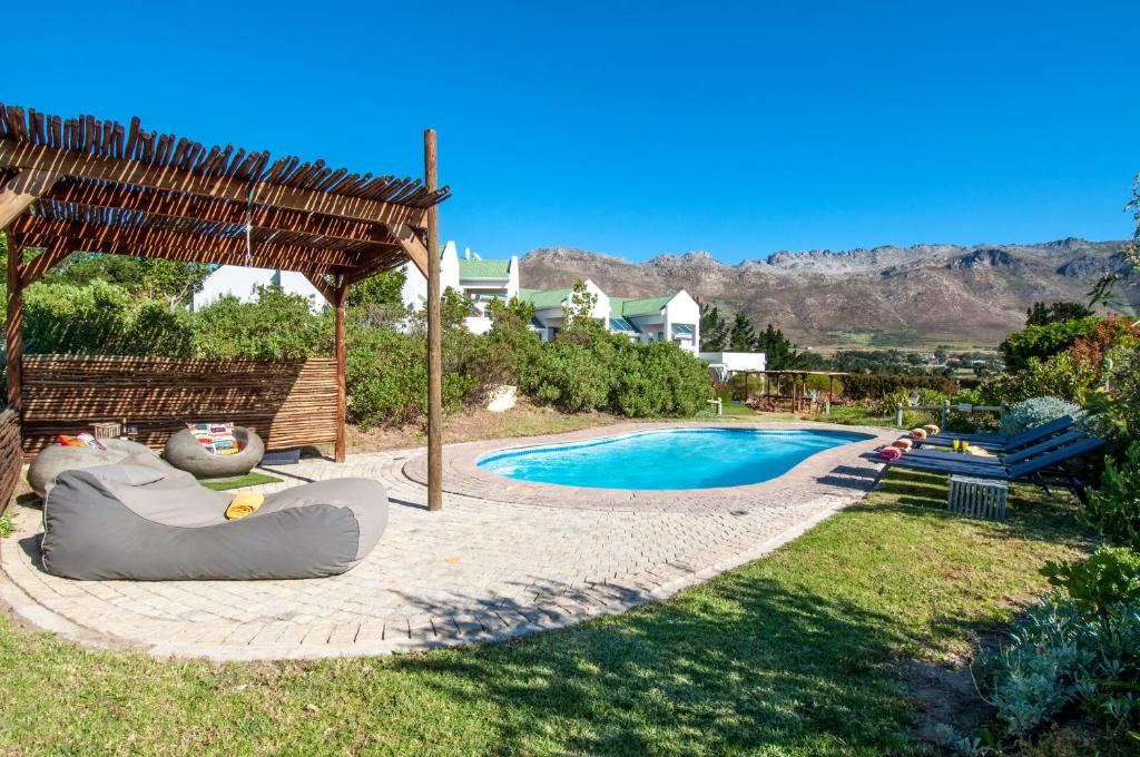 a backyard with a swimming pool and a gazebo at Wind-Rose Guest House in Gordonʼs Bay