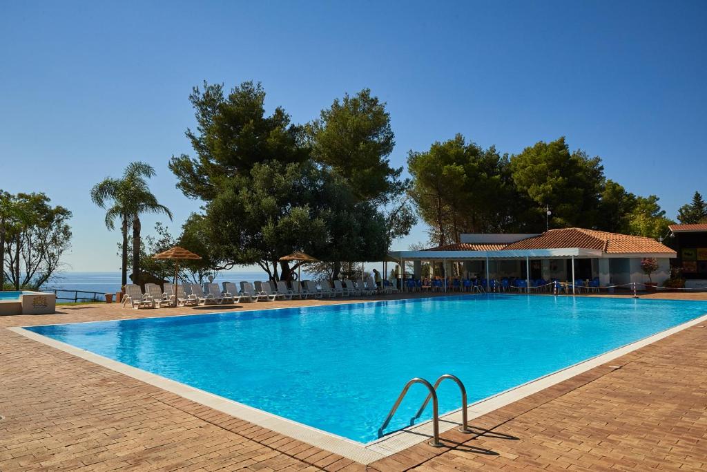 a large blue swimming pool next to a resort at Villaggio L'Oasi in Isola Capo Rizzuto