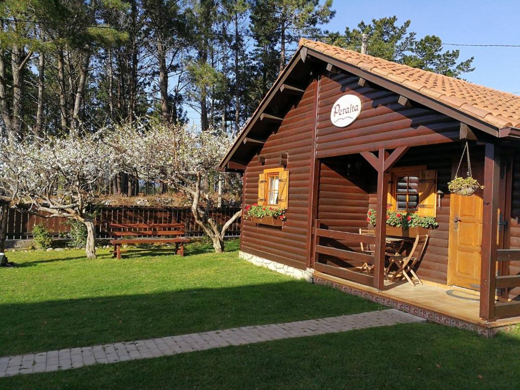 a small wooden cabin with a bench in a yard at Cabañas de Lires in Lires