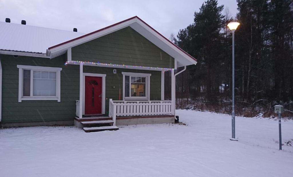 uma pequena casa verde com uma porta vermelha na neve em Apartment A3 Talja em Rovaniemi