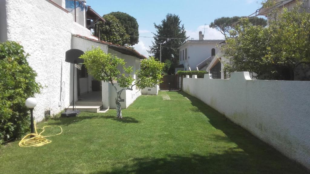 podwórko z zieloną trawą i białą ścianą w obiekcie Villa Colle Circeo 1° w mieście San Felice Circeo