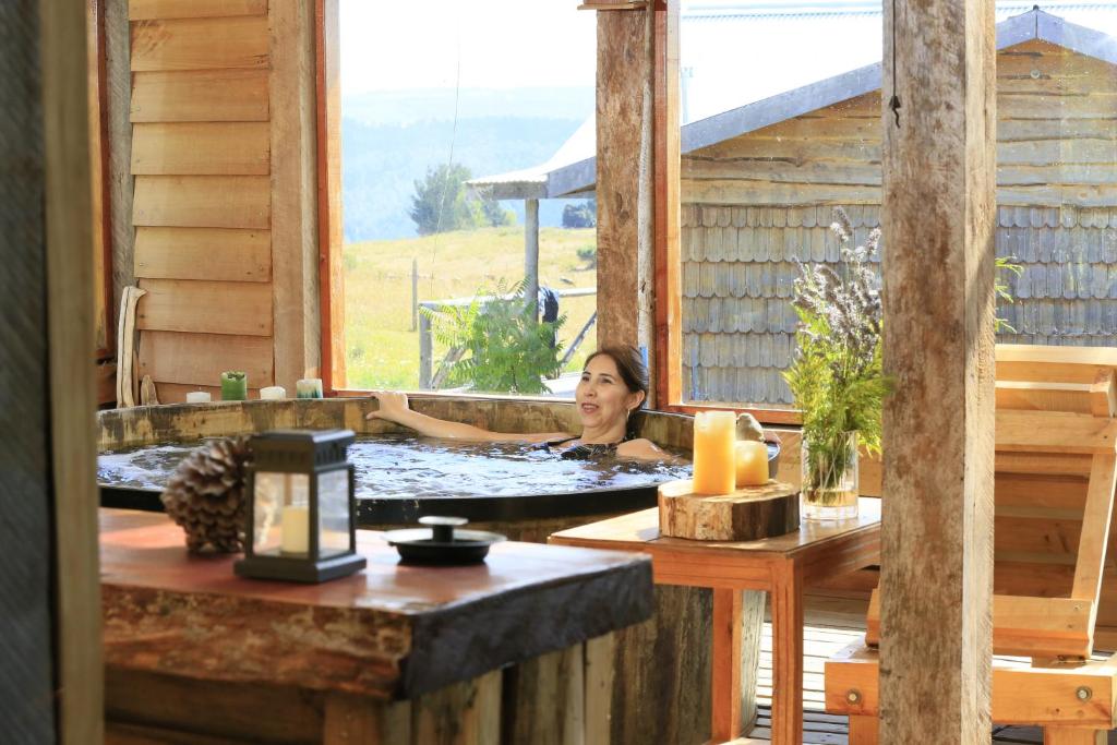 una mujer bañándose en un jacuzzi en una cabaña en Lodge El Sarao A Una Hora De Puerto Varas, en Fresia