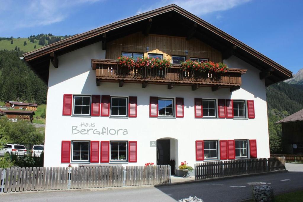 um edifício branco com persianas vermelhas e uma varanda em Ferienwohnungen Haus Bergflora em Bach