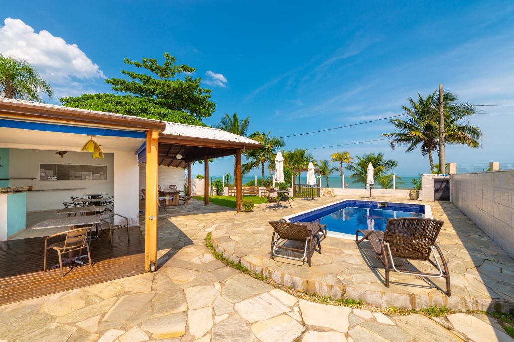 a patio with chairs and a swimming pool at Pousada Pé Na Areia in Caraguatatuba
