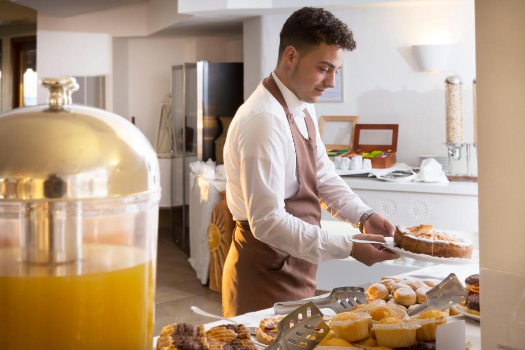 a man in a kitchen holding a plate of food at Hotel Abi d'Oru in Porto Rotondo