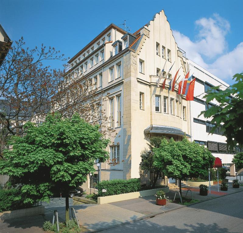 un gran edificio blanco con banderas. en Hotel Viktoria en Colonia