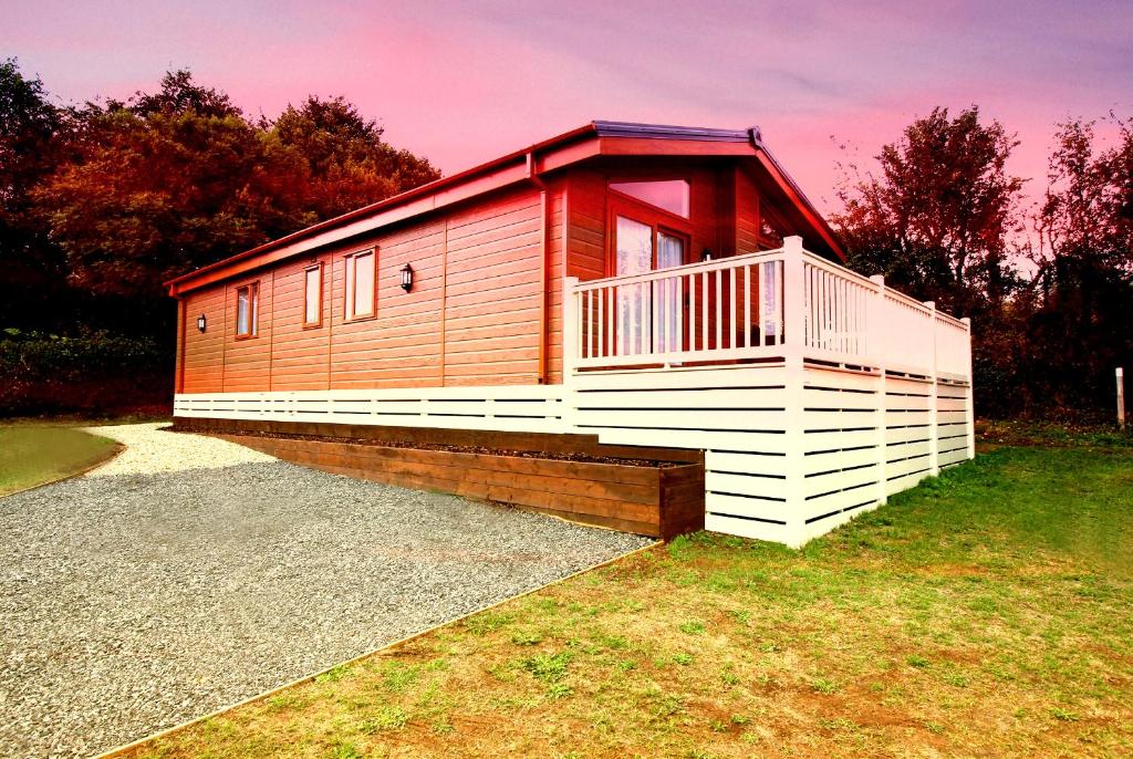 uma pequena cabina com um deque vermelho e branco em Bucklegrove Holiday Park em Cheddar