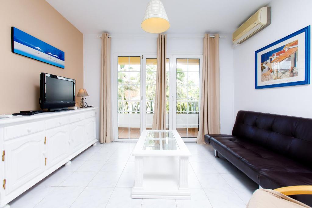 a living room with a black couch and a tv at AT Almoraide Rooms Suites in Nerja