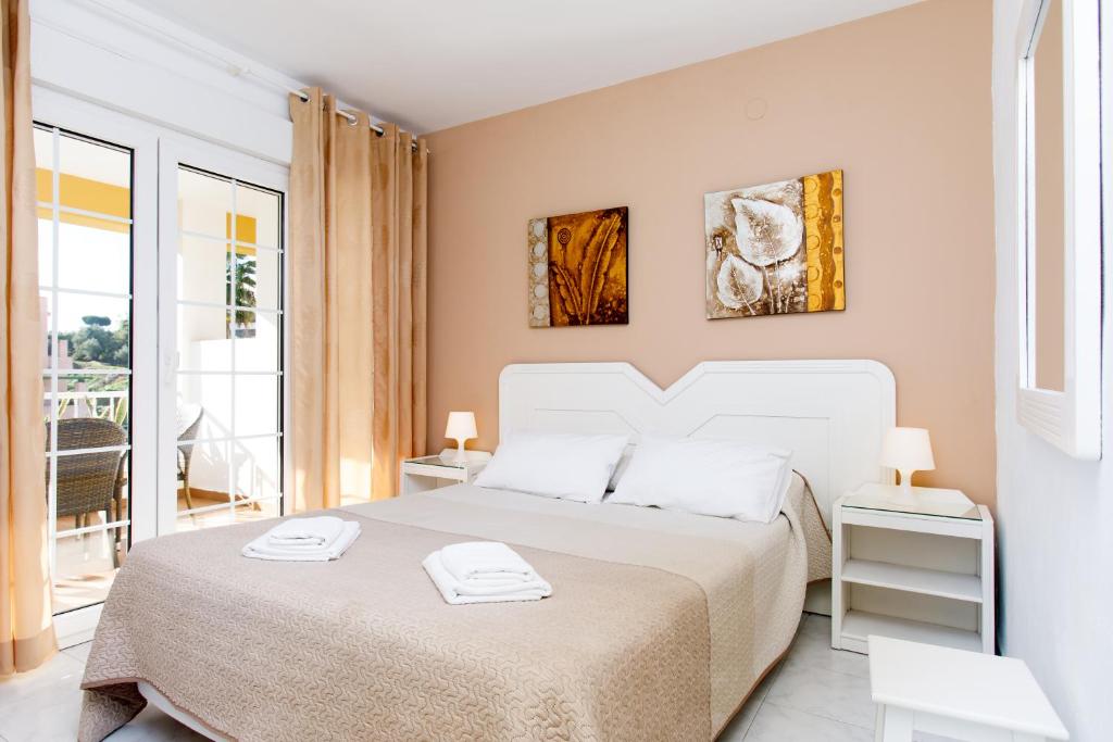 a white bedroom with a bed and a balcony at AT Almoraide Rooms Suites in Nerja