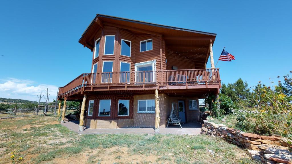 ein großes Holzhaus mit einem Balkon und einer amerikanischen Flagge in der Unterkunft Juniper Ridge 5 BR Family Cabin in Blanding