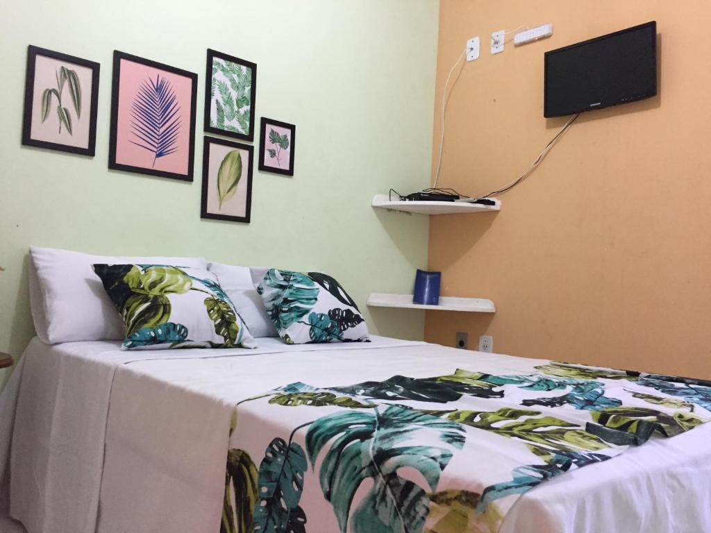 Pousada Rio Alegre في سانتو أمارو: غرفة نوم مع سرير وتلفزيون على الحائط