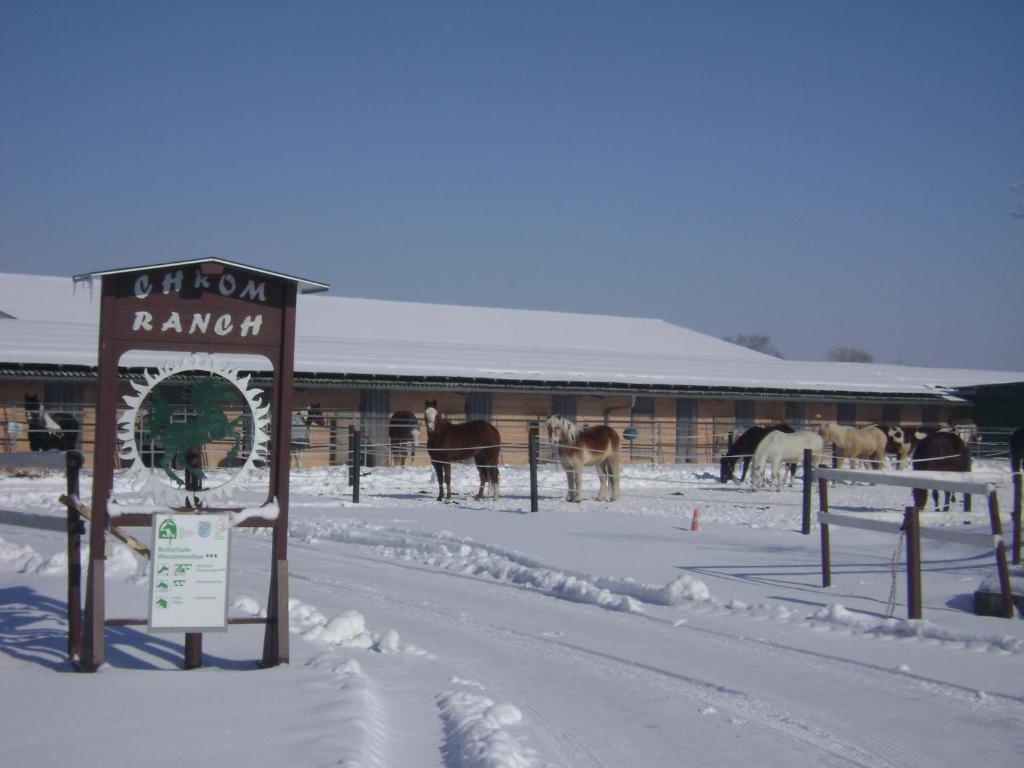 a sign in the snow in front of a barn with horses at Chrom Ranch Reiterhof in Memmingen