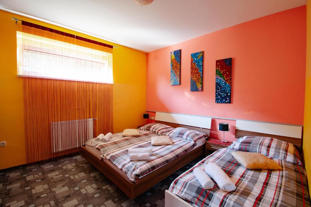 2 camas en una habitación con paredes de color naranja y amarillo en Apartments Pri Adamsovih en Čatež ob Savi