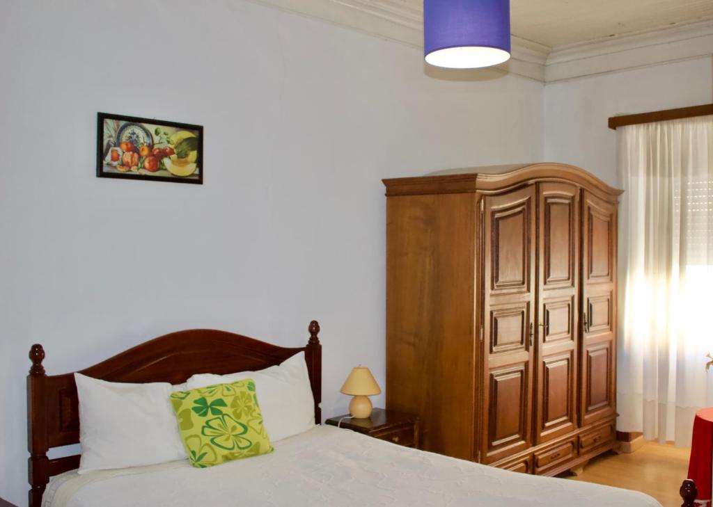 a bedroom with a bed and a wooden cabinet at Residencial Rivoli in Fundão