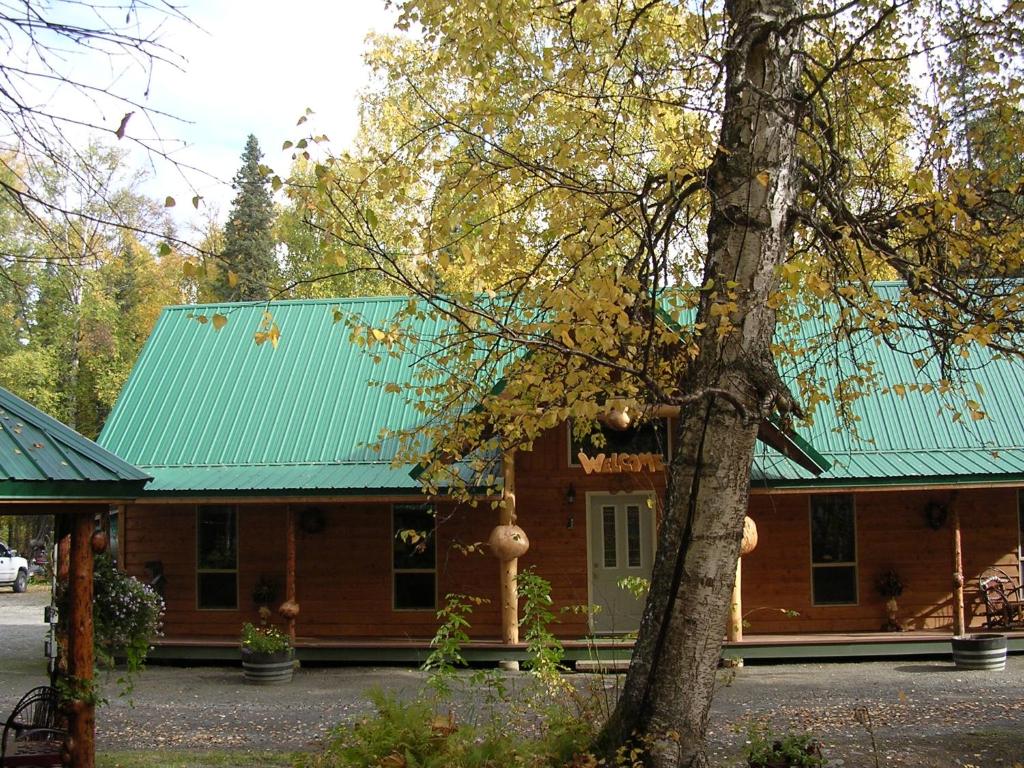 a house with a green roof and a tree at Alaska's Northland Inn in Trapper Creek