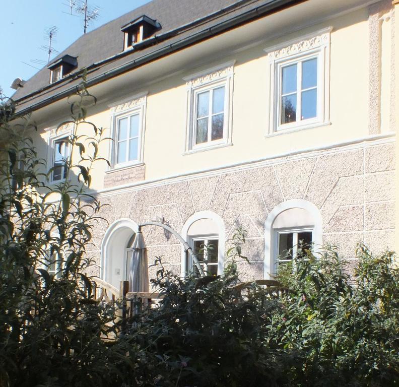 duży ceglany budynek z białymi oknami i krzakami w obiekcie Müllers Ferienhaus Salzburgerland w mieście Unken