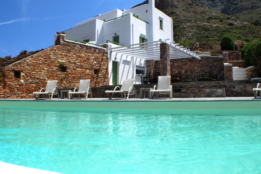 una piscina con sillas y una casa en el fondo en Xerolithia, en Kamarai