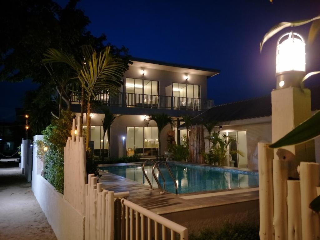 ein Haus mit einem Pool und einem Leuchtturm in der Nacht in der Unterkunft Sea Sand House Resort in Klong Wan