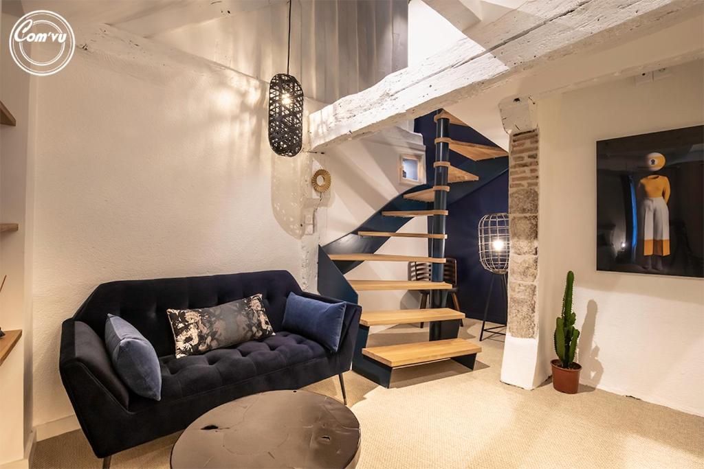 a living room with a couch and a spiral staircase at LE CELESTIN - Centre Historique - in Rennes