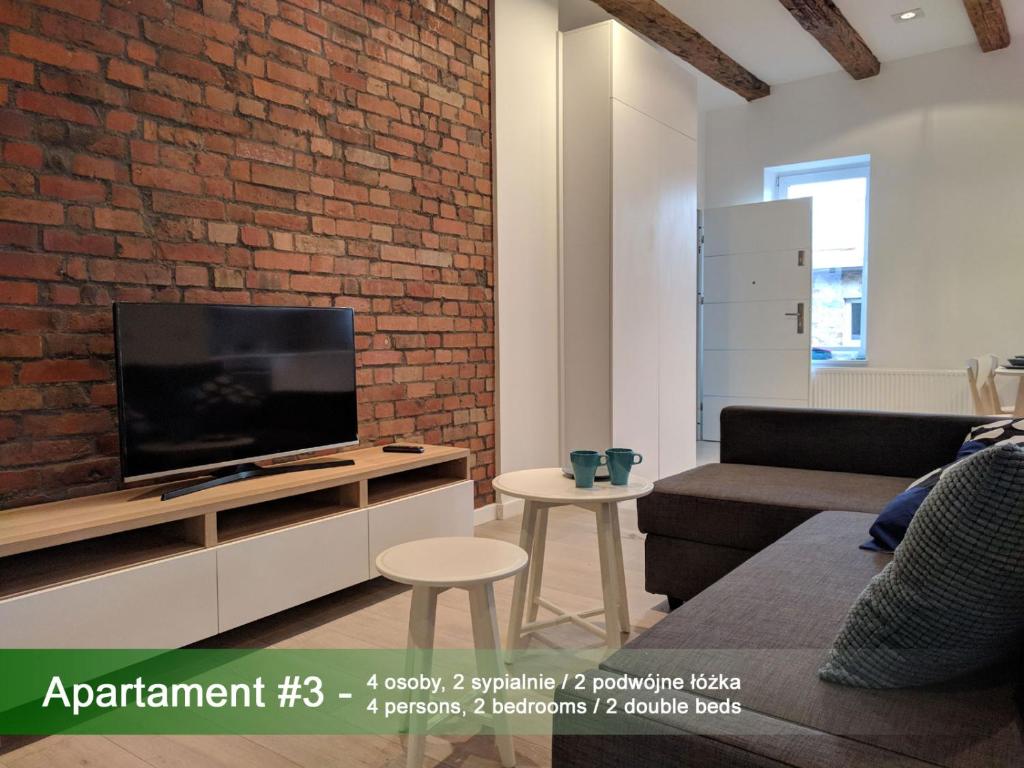 ein Wohnzimmer mit einem TV und einer Ziegelwand in der Unterkunft Apartament Z Widokiem Na Rynek in Gliwice
