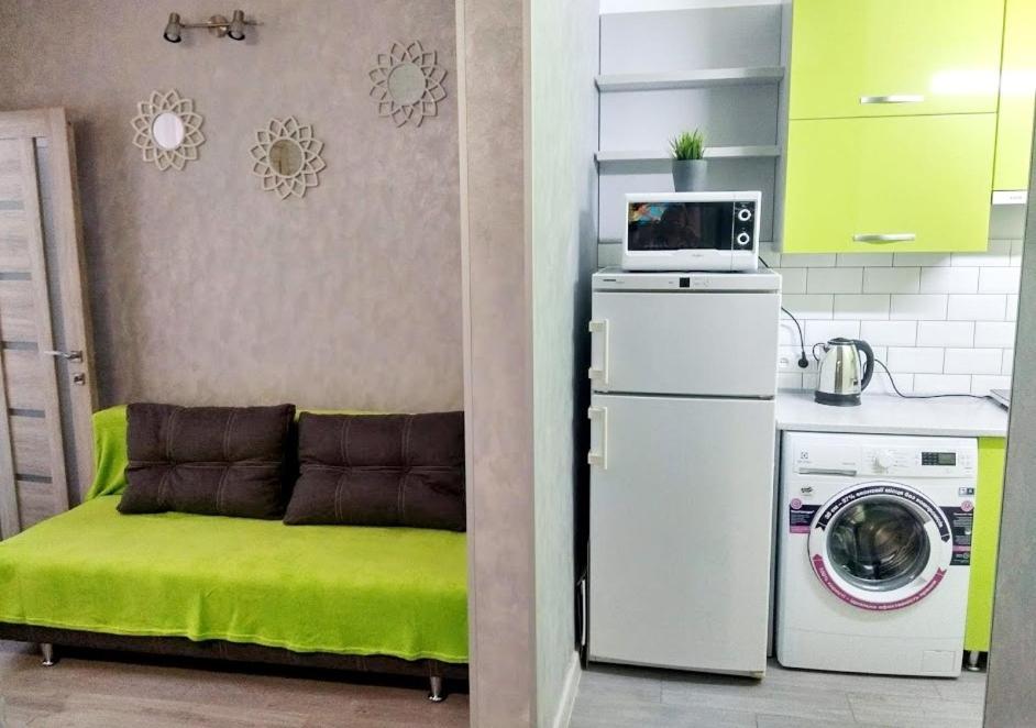 a kitchen with a green ottoman and a washing machine at Apartment "Comfort" in the Center in Chernivtsi