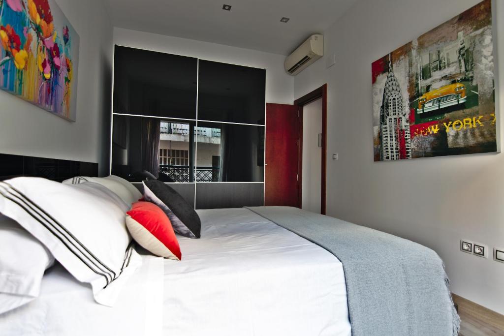 um quarto com uma grande cama branca com almofadas vermelhas em apartamento completo centrico em Maracena