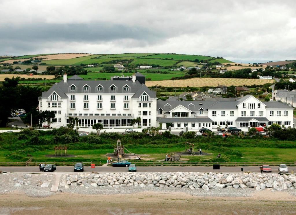 a large white building with cars parked in front of it at Garryvoe Hotel in Ballycotton