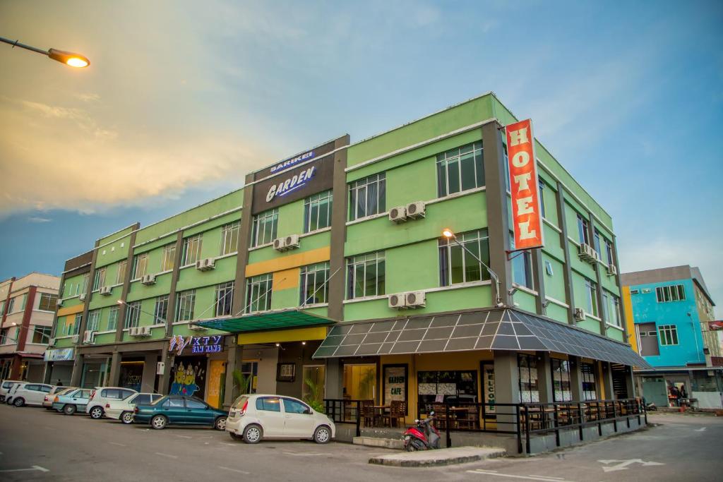 un bâtiment vert avec des voitures garées devant lui dans l'établissement SARIKEI GARDEN HOTEL, à Sarikei