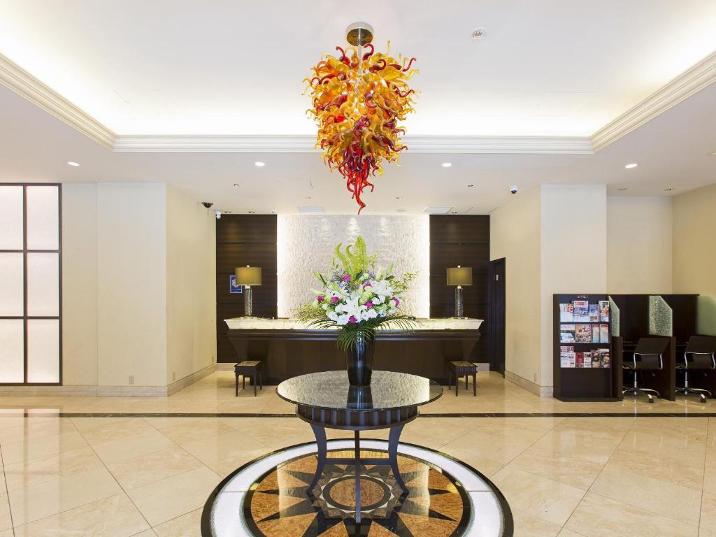 a lobby with a table with a vase of flowers at Sol Vita Hotel Naha in Naha