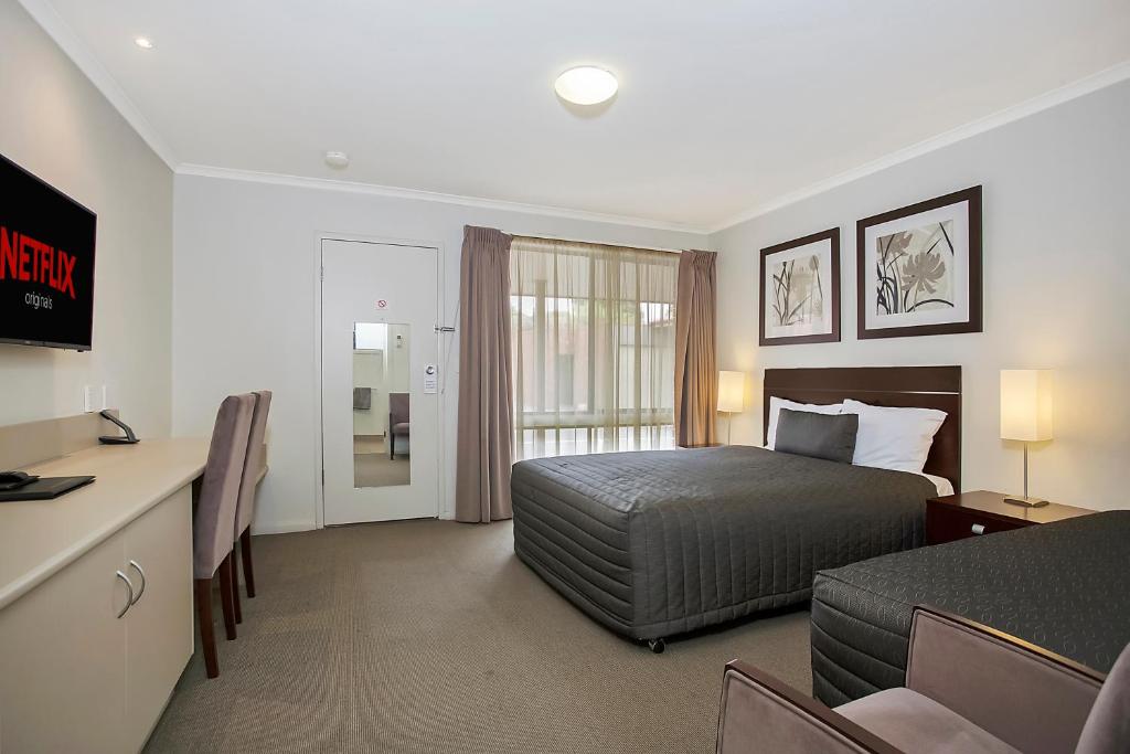 Habitación de hotel con cama y escritorio en Elm Tree Motel, en Warrnambool