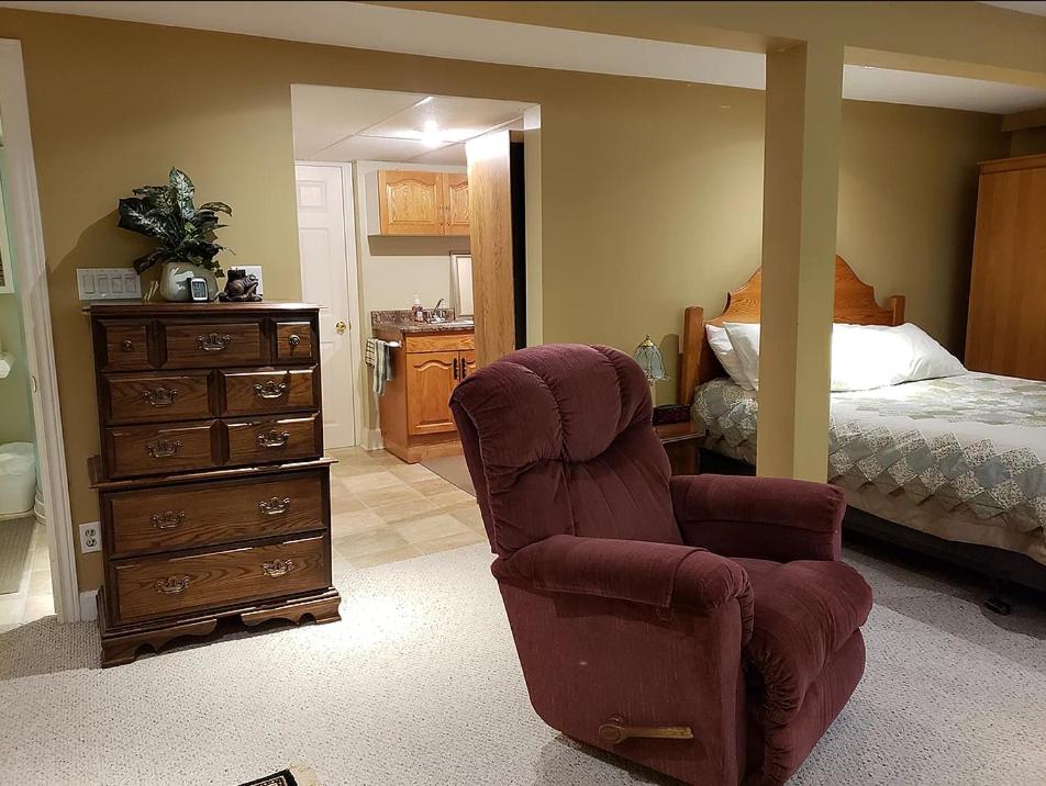 a bedroom with a bed and a chair and a dresser at Forest Hill Bed and Breakfast in Kitchener