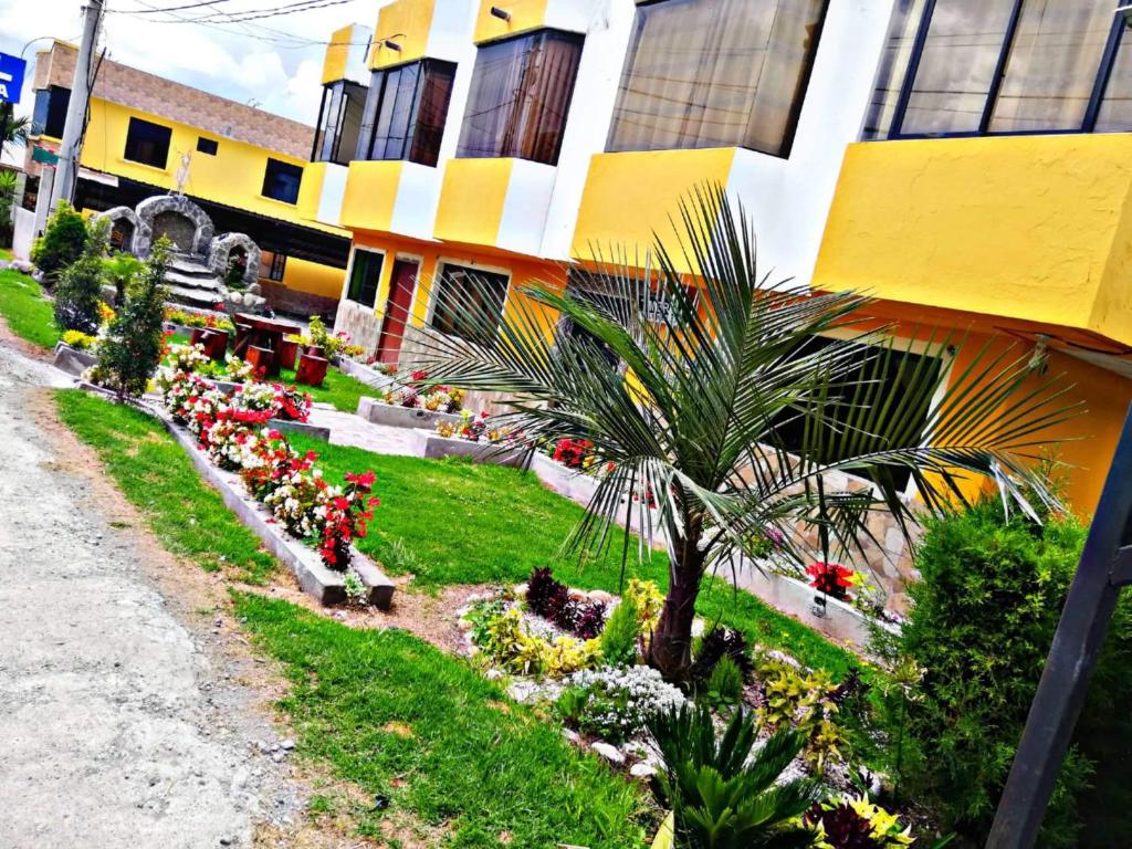 een gebouw met bloemen en een palmboom in een tuin bij Hostal Mariscal Sucre in Tababela