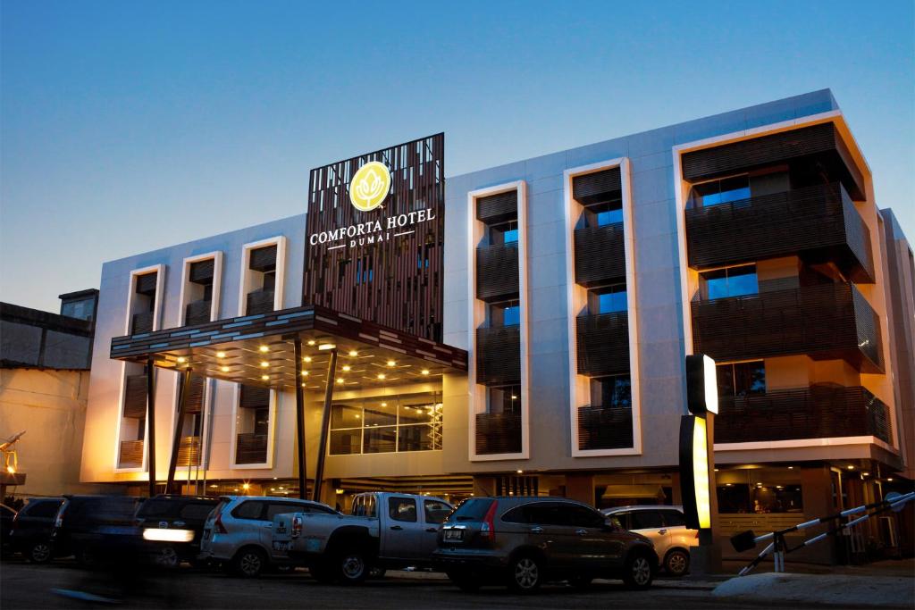 a building with trucks parked in front of it at Comforta Dumai in Dumai