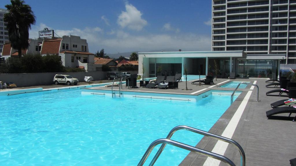 a large swimming pool with chairs and a building at Club Océano La Serena 2do piso in Coquimbo