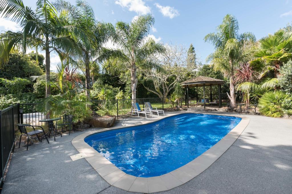 einen Pool in einem Garten mit Palmen in der Unterkunft Kauri Park Motel in Kerikeri