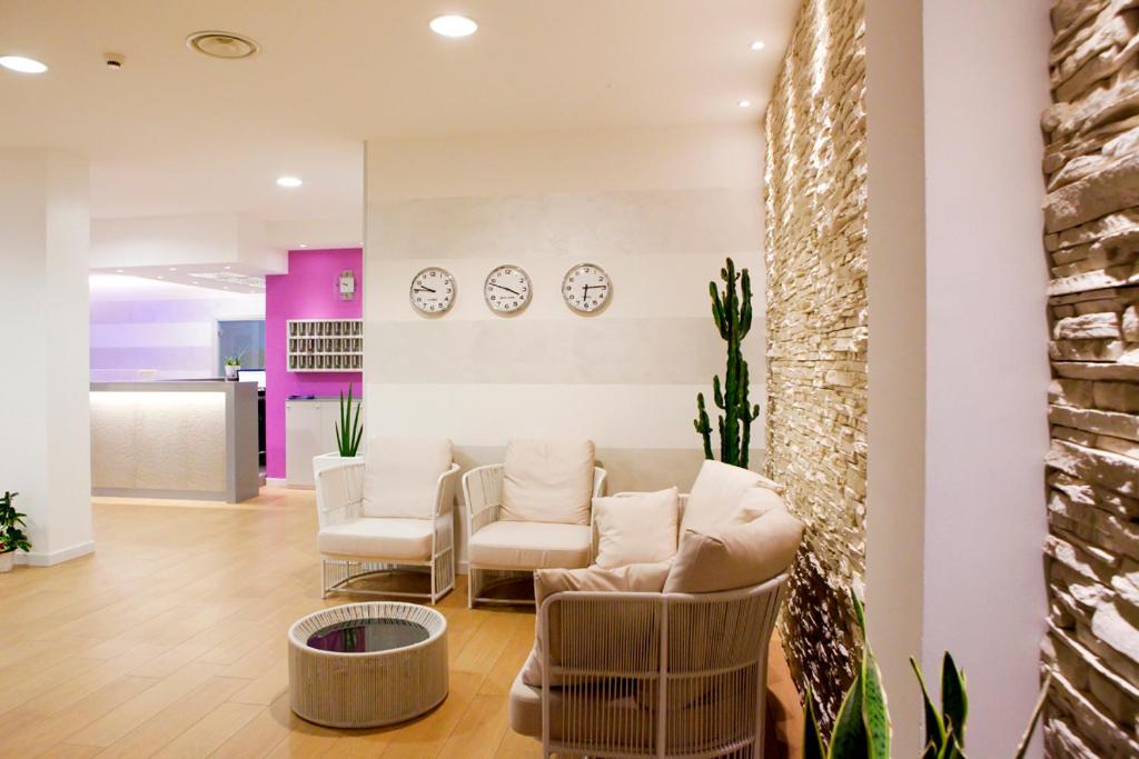 a waiting room with chairs and clocks on the wall at Hotel Lux in Caorle