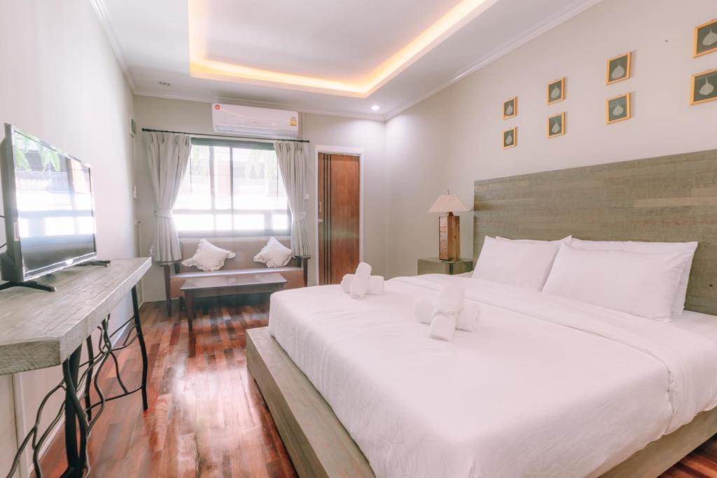 a bedroom with a large white bed and a television at 64House in Chiang Mai