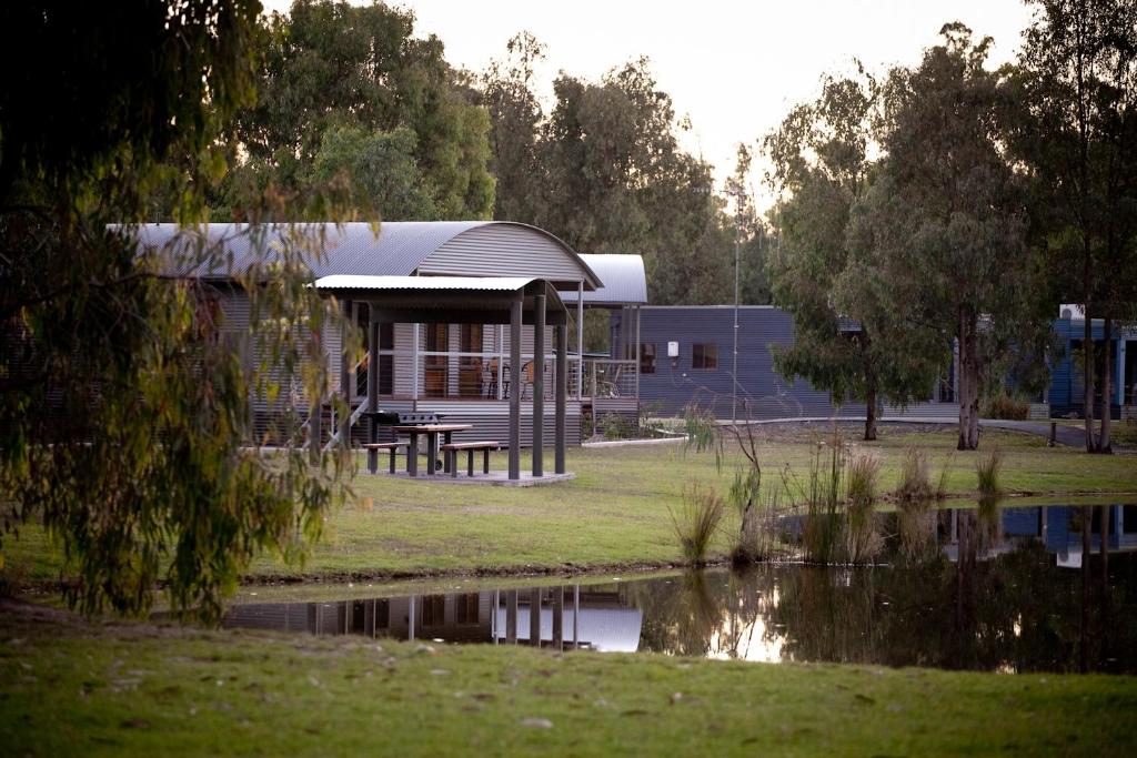 a building with a picnic table next to a body of water at Tasman Holiday Parks - Moama on the Murray in Moama