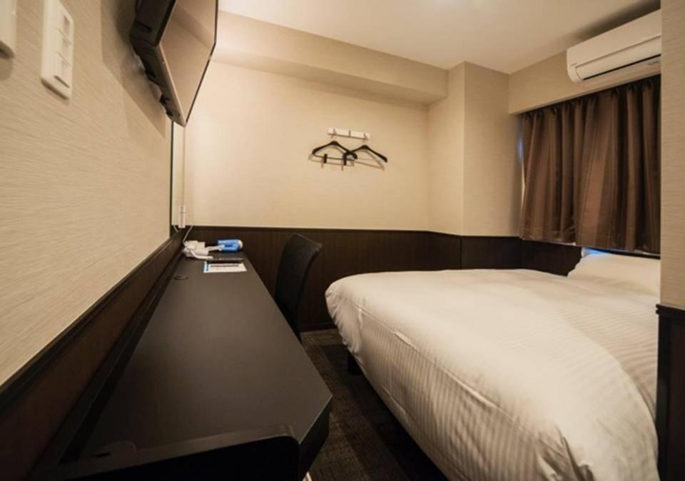 a bedroom with a bed and a desk with a tv at Hotel Excellence Kyoto Station Nishi in Kyoto